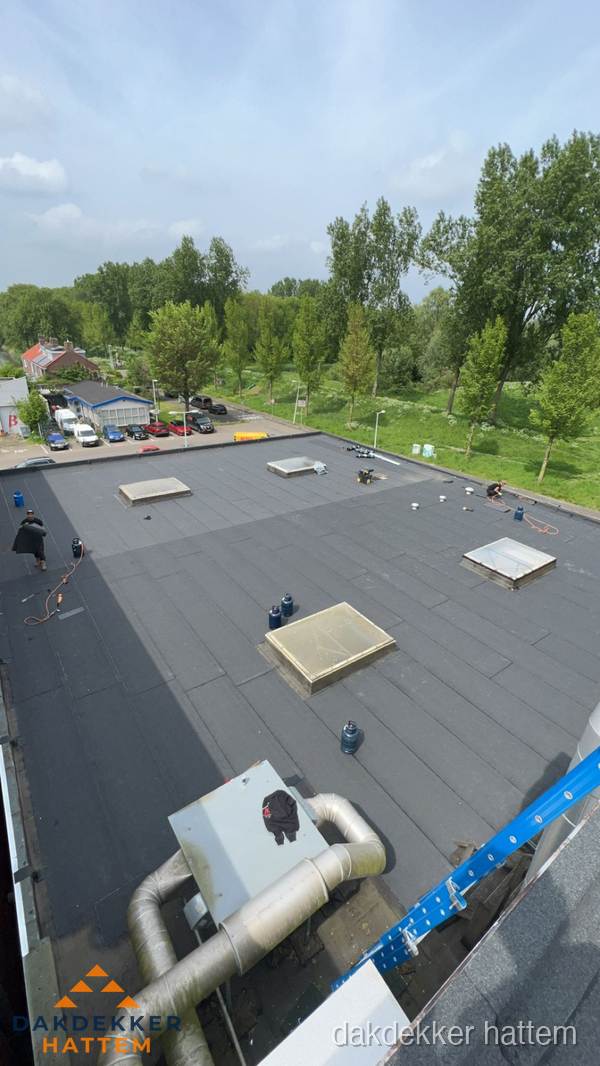 Dakdekker aan het werk op groot plat dak met bitumen in Hattem