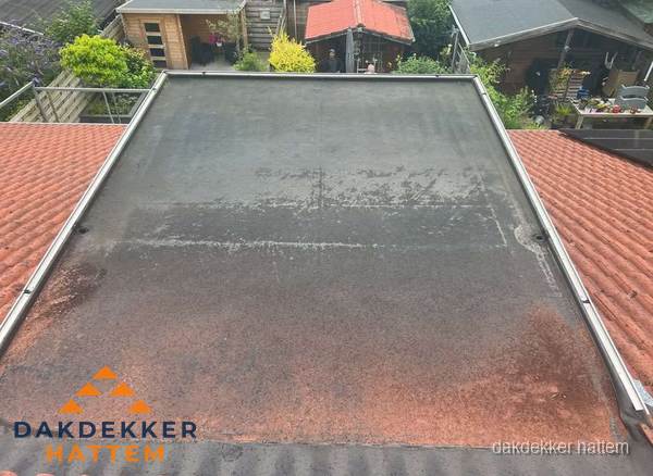 Verouderd plat dak met slijtage tussen schuine daken in Hattem Verouderd plat dak met slijtage tussen schuine daken in Hattem