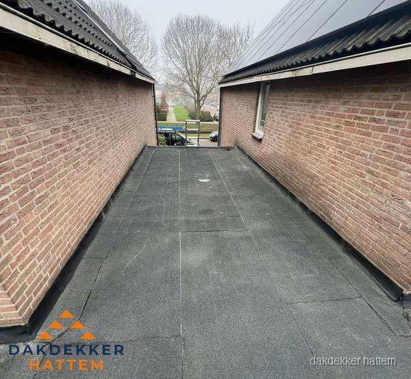 Plat dak met bitumen dakbedekking tussen bakstenen muren in Hattem Plat dak met bitumen dakbedekking tussen bakstenen muren in Hattem